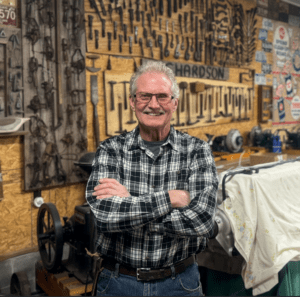 Man smiling in vintage workshop with tools.