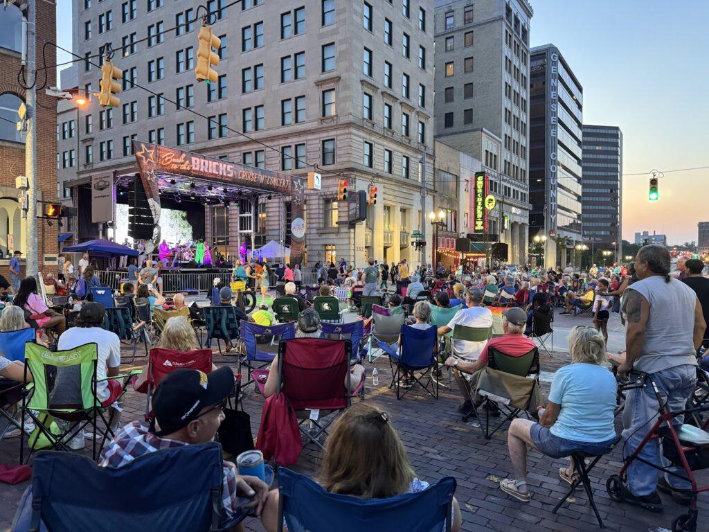 Outdoor concert with seated audience in city.