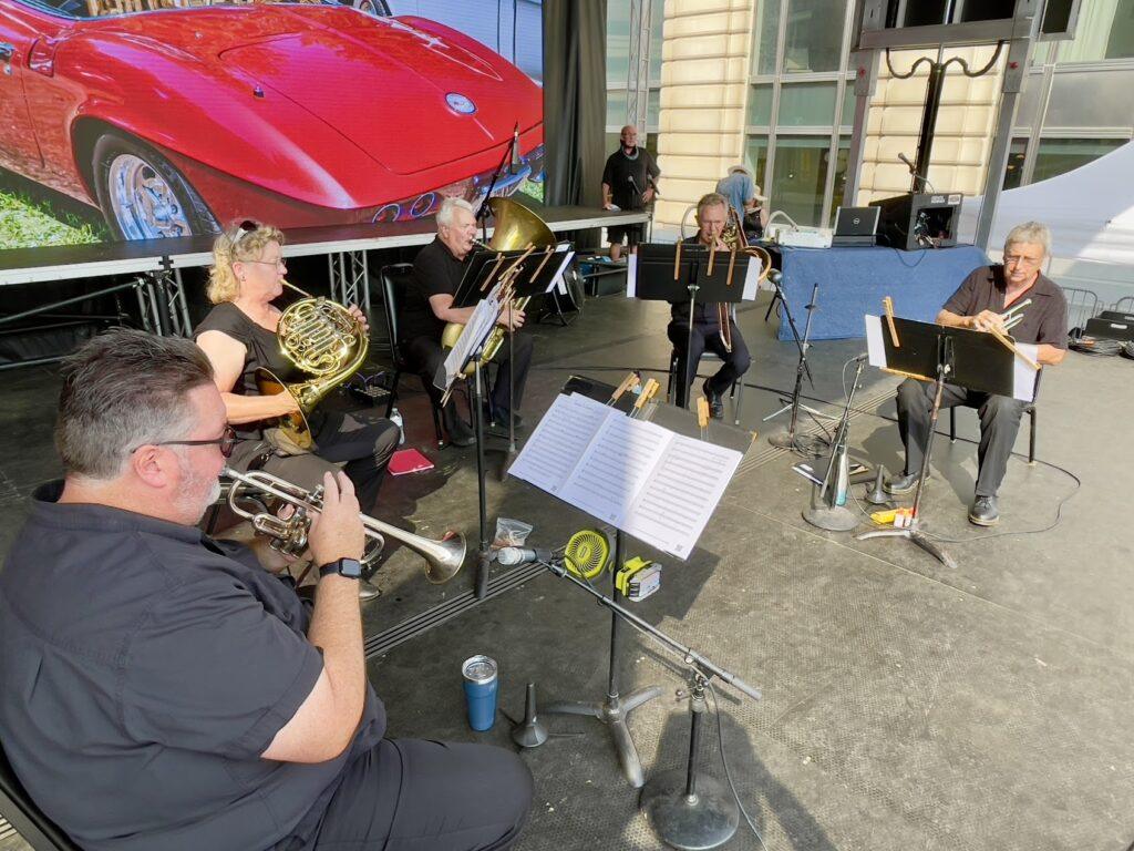 Brass ensemble performing on outdoor stage.
