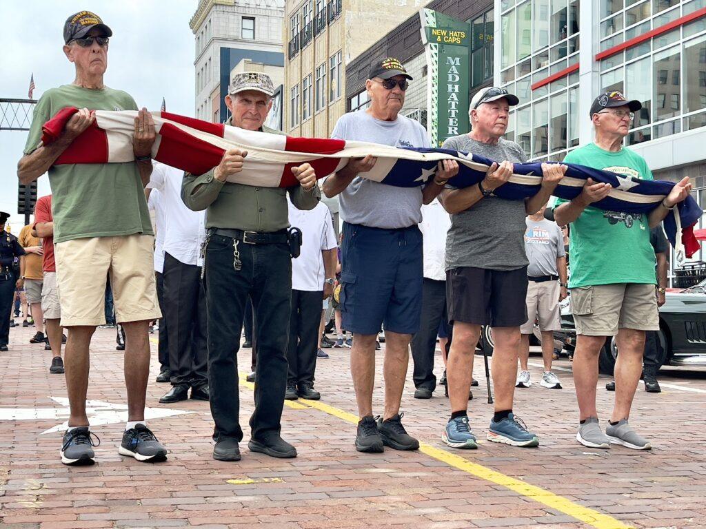 Veterans holding a folded American flag outdoors.