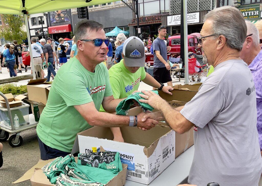 People distributing T-shirts at outdoor event.