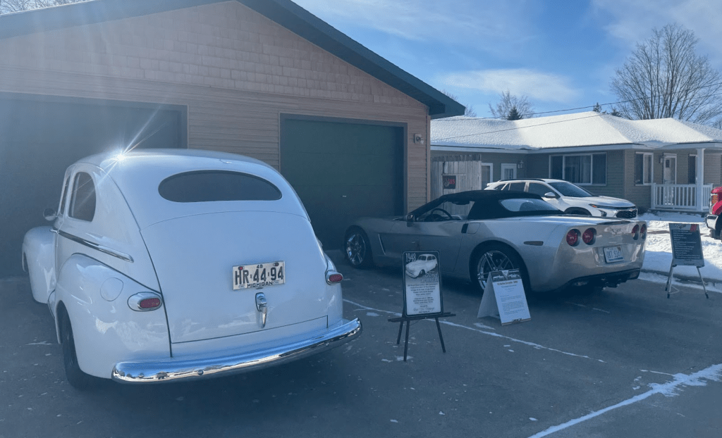 Two vintage cars parked outside a garage.