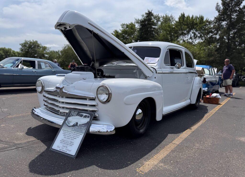 White vintage car with hood open.
