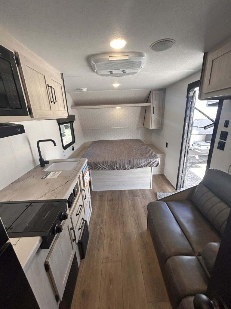 Camper interior with bed and kitchenette.