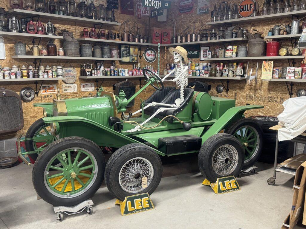 Skeleton driving vintage green car in garage.